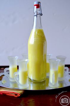 a glass bottle filled with liquid sitting on top of a metal tray next to glasses