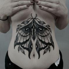 a woman's stomach with a butterfly tattoo on her belly and hands covering her eyes