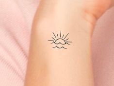 a woman's arm with a small sun tattoo on it