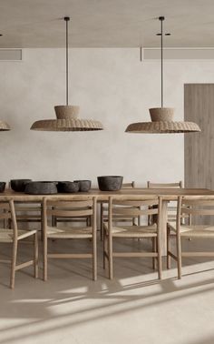 a dining room table and chairs with baskets hanging from the ceiling over them, in front of a white wall