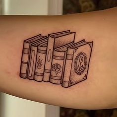 a tattoo on the arm of a person with three books