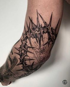 a man's arm with black ink and spikes on the top half of it