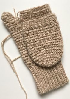 a pair of knitted mittens sitting on top of a white table next to a string