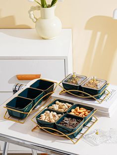 three trays filled with food sitting on top of a table next to a vase