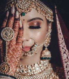 a woman with her hands on her face wearing jewelry and holding her hand up to her face