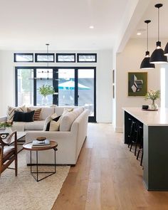 a living room filled with furniture next to a kitchen and dining room table on top of a hard wood floor