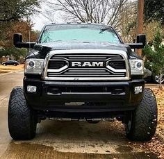 the ram truck is parked on the side of the road in front of some trees