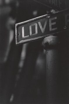 black and white photograph of a street sign with the word love on it's side