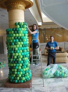 a man and woman standing next to a giant balloon column