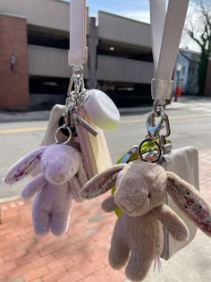 two stuffed animals hanging from the handles of some keychains on a street corner