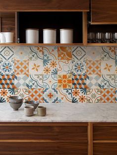 a kitchen counter with some cups and bowls on top of it next to a cabinet