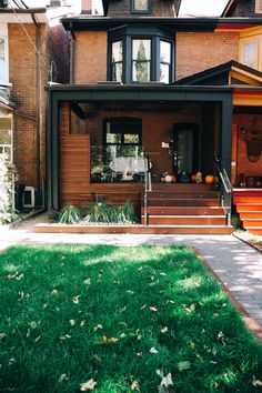 a house that has grass in front of it and stairs leading up to the door