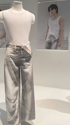 the mannequin is dressed in silver pants and a white tank top on display