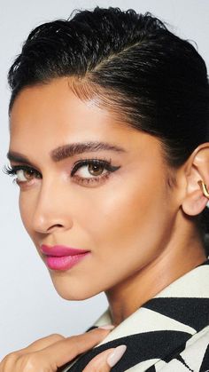 a woman with black hair and pink lipstick is posing for the camera, she has her hand on her shoulder