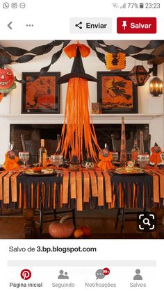 an orange and black halloween table setting with decorations on the mantle, pumpkins hanging from the ceiling