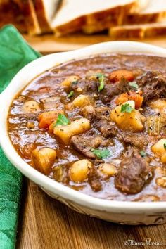 a white bowl filled with stew next to slices of bread