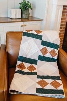 a brown leather chair with a quilt on it