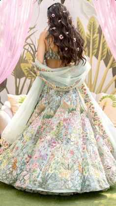 a woman in a floral dress is sitting on the floor with her back turned to the camera