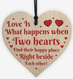 a wooden hanging heart with two hearts on it and the words, love is what happens when two hearts find their happy place right beside each other