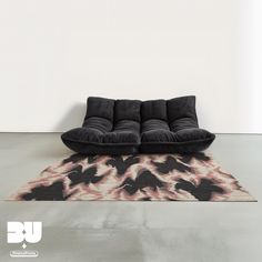 a black couch sitting on top of a rug next to a white wall and floor