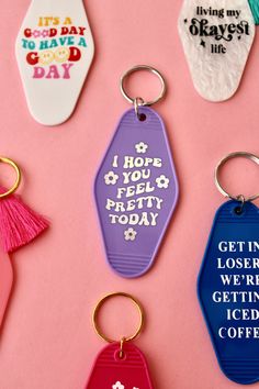 six different colored key chains with words on them and tassels attached to them