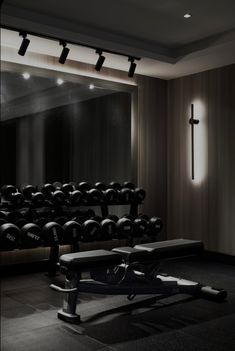 an empty gym with rows of dumbs and benches in front of a cross - shaped mirror