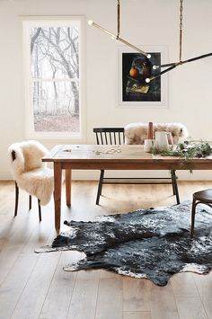 a dining room table with chairs and an animal rug on the floor in front of it