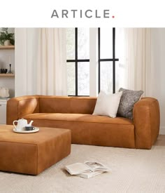 a brown leather couch sitting on top of a white rug in front of a window