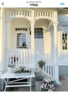 a white house with flowers on the porch