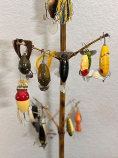 there are many different types of ornaments hanging on the tree branch in front of the wall