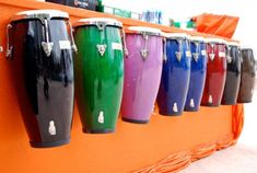 many different colored vases are lined up on the wall in front of an orange shelf