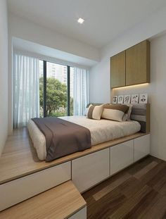 a bed sitting on top of a wooden platform in a bedroom next to a window