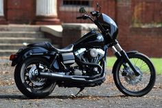 a black motorcycle parked on the side of a road in front of a brick building