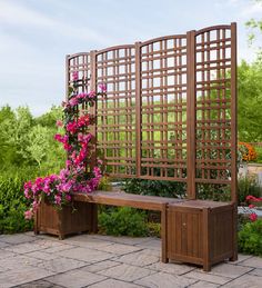 a wooden bench sitting next to a flower pot on top of a stone floor covered in pink flowers