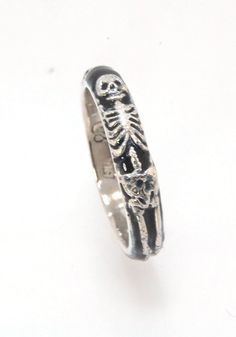 This is the middle width of my Memento Mori skeleton rings at 4mm wide. The Skeleton is flanked by crossed bones on one side and an hourglass on the other. Each ring in this collection is carved in wax by hand and cast using the ancient lost wax process. I then make a mold from which I can pull a wax copy of the original that can be resized to fit you and cast in silver or gold. These Skeleton rings are enameled with black glass in the recesses and polished to a high shine inside and brushed fin Wax Ring Carving Ideas, Skeleton Rings, Wax Carved Ring, Ancient Rings, Memento Mori Ring, Memento Mori Jewelry, Skeleton Jewelry, Skeleton Ring, Dr Jewelry