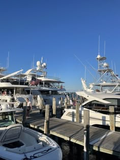 several boats docked at a pier with people standing on the dock