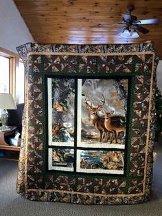 a quilted wall hanging in the corner of a room with two deer pictures on it