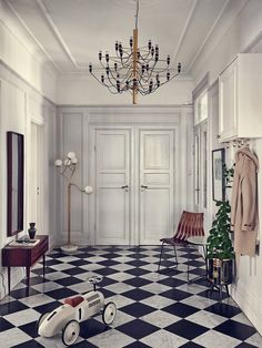 a black and white checkered floor in a room with a chandelier hanging from the ceiling