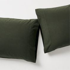 two dark green pillows sitting next to each other