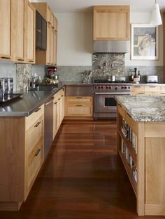 a kitchen with wooden cabinets and stainless steel appliances in the center, along with hardwood flooring