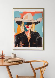 a painting of a woman wearing a cowboy hat is hanging on the wall above a table