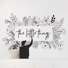 a person holding up a sign with the words the little things above it in black and white