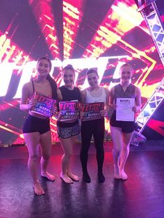 four girls standing on stage holding up signs