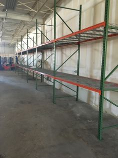 an empty warehouse filled with lots of metal shelvings and red shelves on the wall