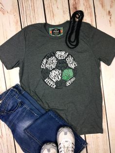 a t - shirt and jeans are sitting on a wooden floor next to some shoes