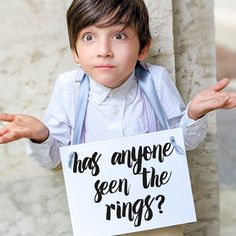 a little boy holding a sign that says has anyone seen the rings? with his hands