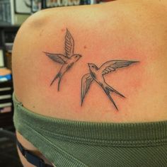 two birds flying next to each other on the back of a woman's shoulder