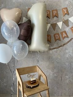 balloons and streamers are hanging from the wall above a chair with a cake on it