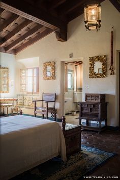 a bedroom with a bed, dresser and mirror in it's center wall is shown