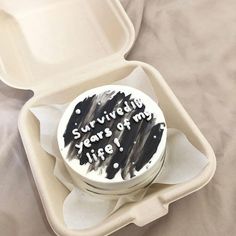 a cake in a foam container with writing on the side and inside it, sitting on a bed